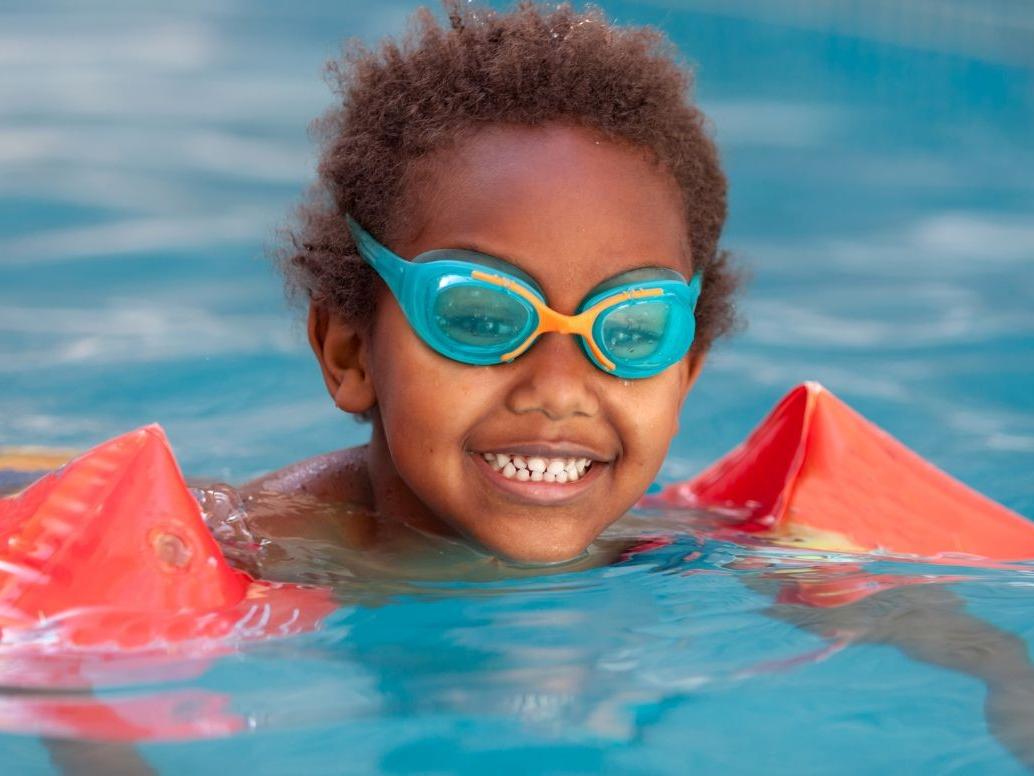 Boy with goggles swimming in pool