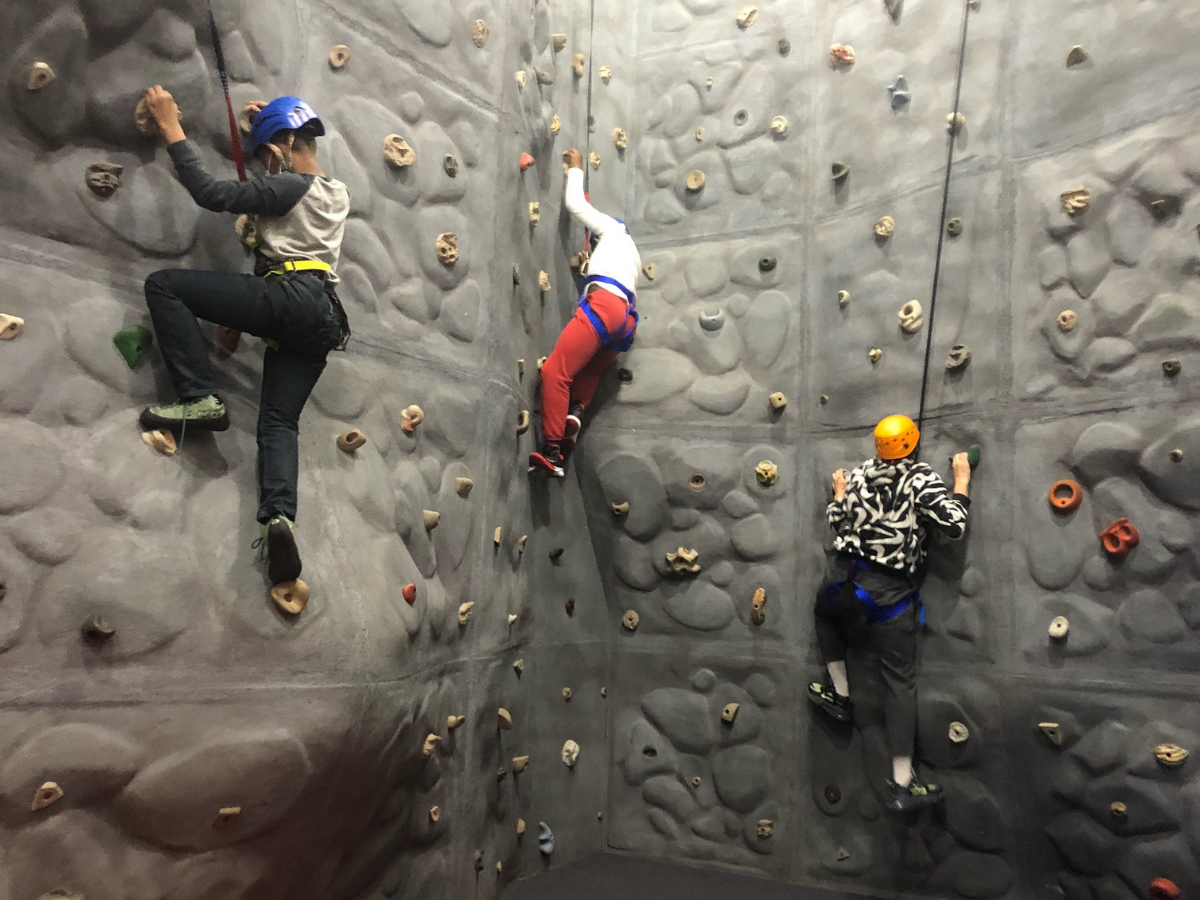Three kids climb rock wall